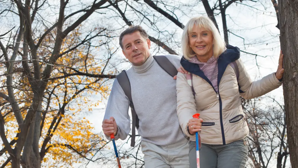 An older couple in outdoor jackets hiking together through autumn woods