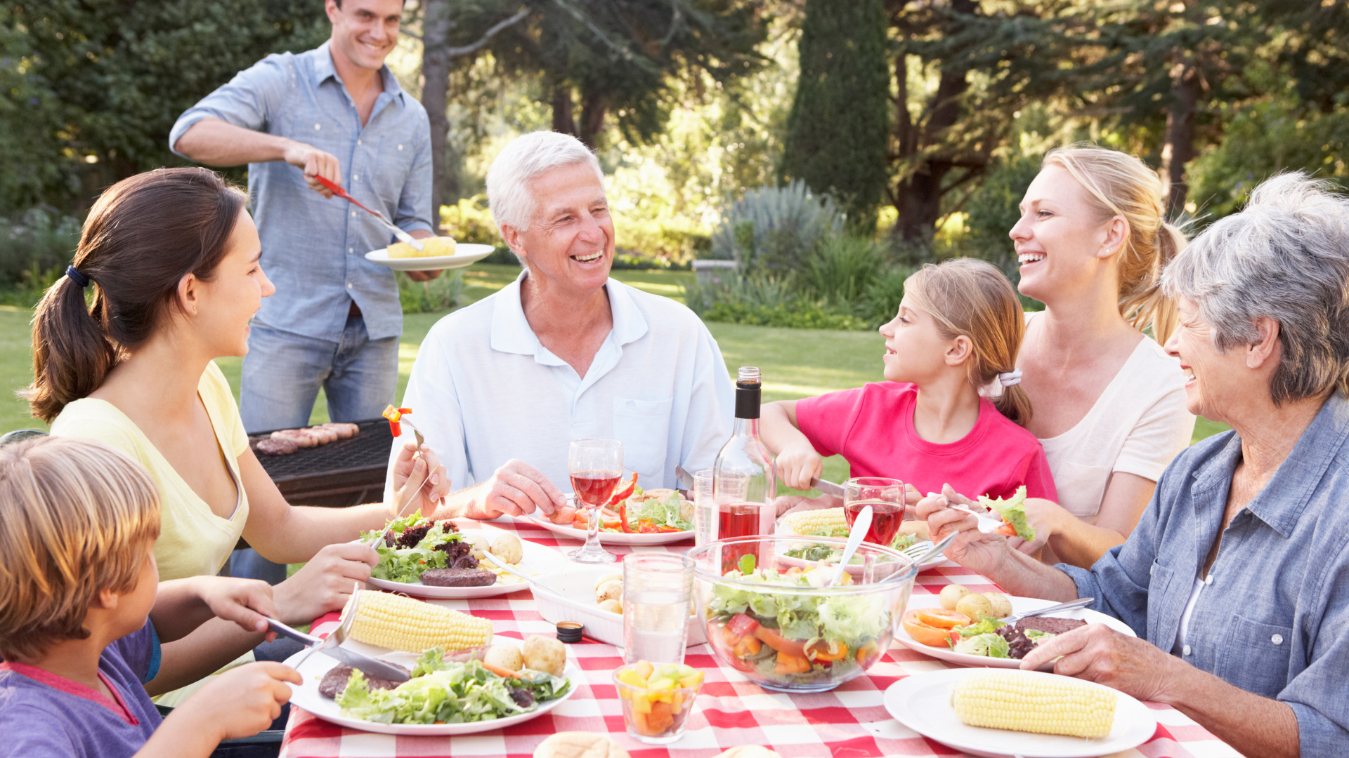 A multigenerational family sharing a meal around an outdoor dining table