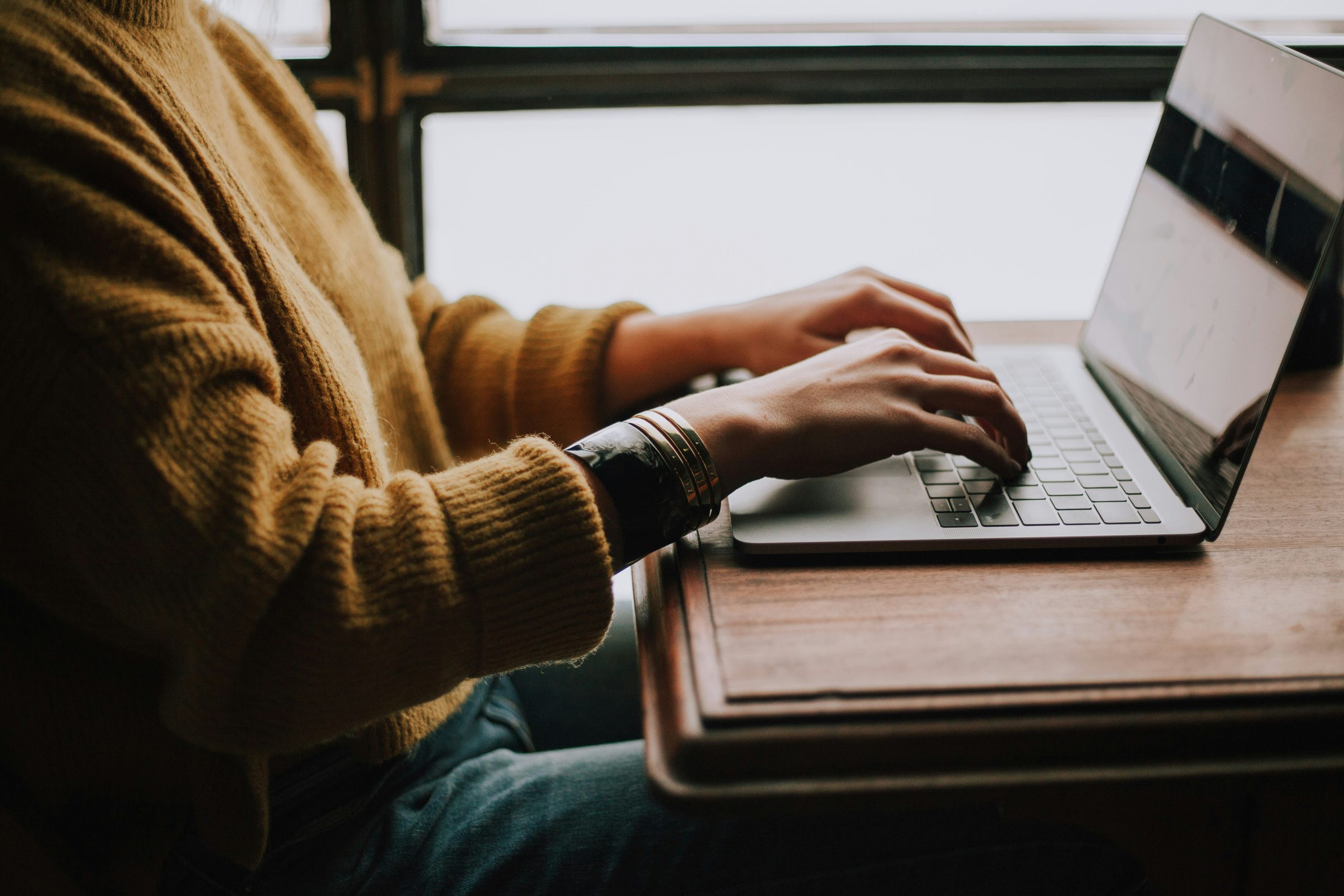 A close-up of a person typing on a laptop at a desk