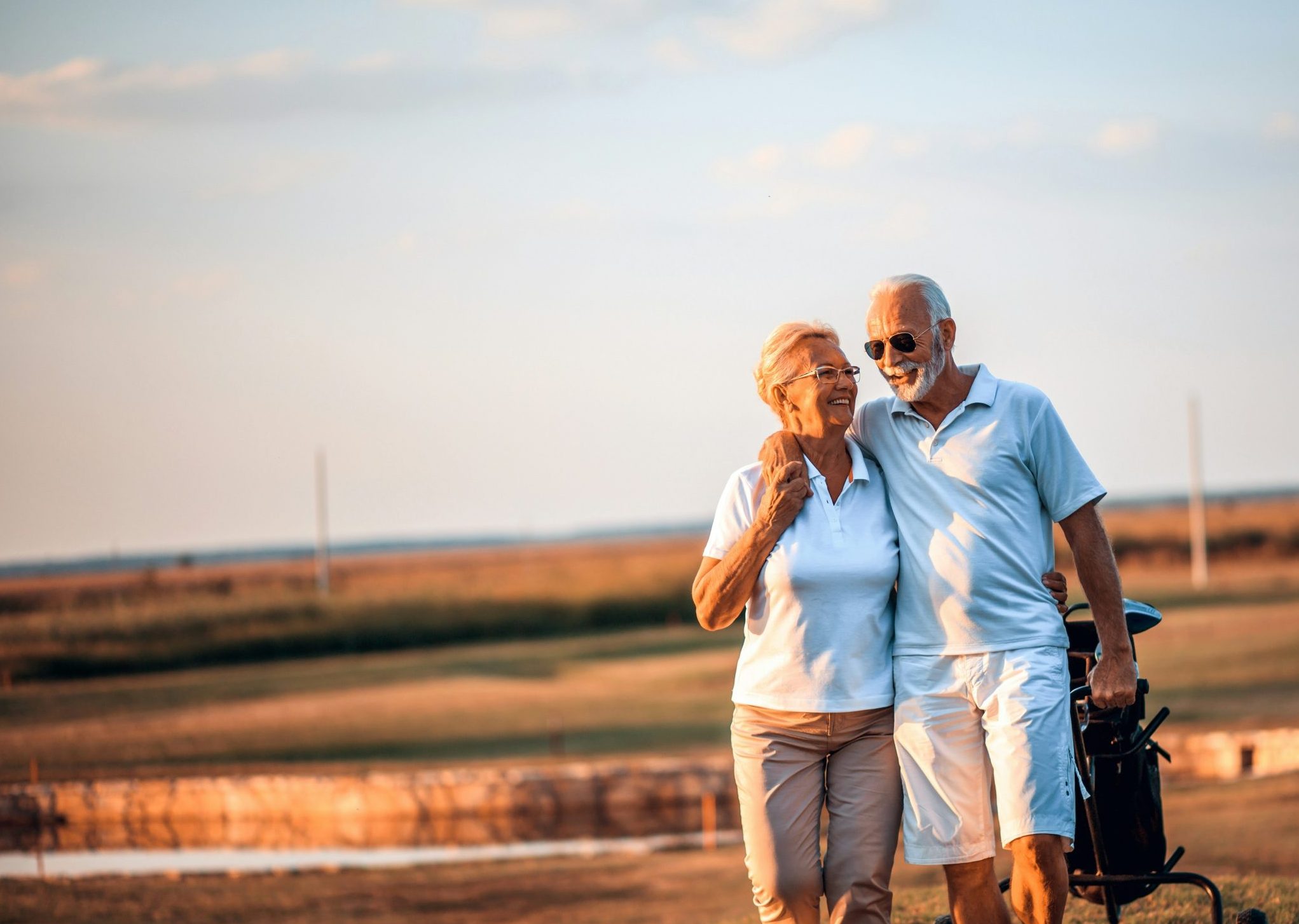 A senior couple walking together on a beach at sunset