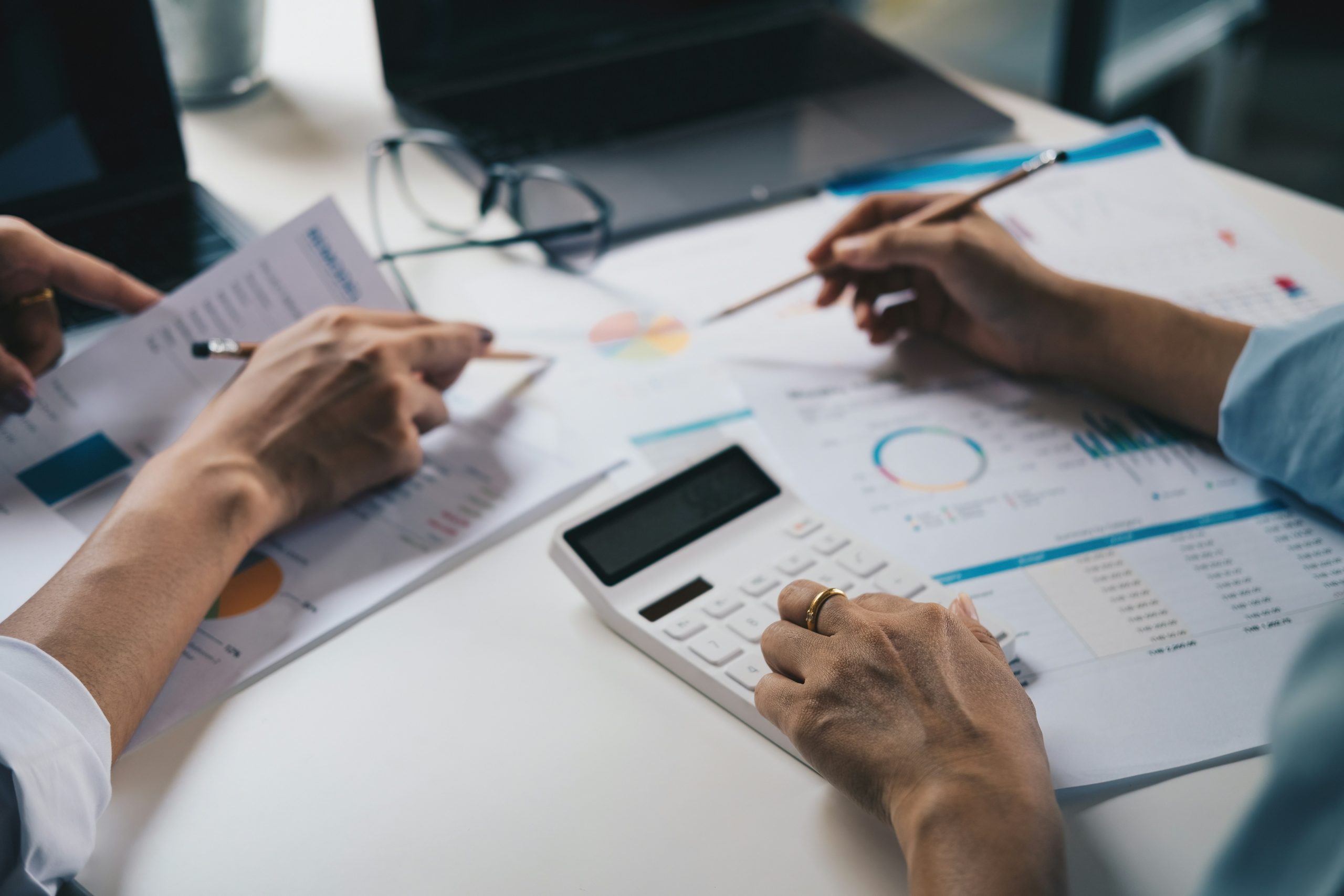 Two people reviewing financial reports with a calculator
