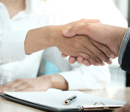 A handshake over a desk with documents